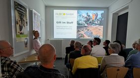 Referentin neben der Präsentation «Gift im Stoff» vor dem Publikum des Usitawi-Abends bei ALOCO.