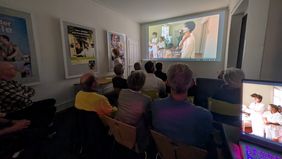 Gäste schauen einen projizierten Filmausschnitt beim Usitawi-Abend in den Räumen von ALOCO in Bern.